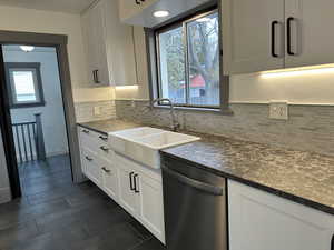 Kitchen with stainless steel dishwasher, white cabinets, and farmhouse sink