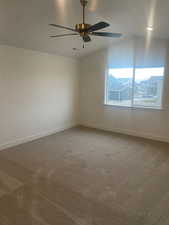 Carpeted empty room featuring ceiling fan and lofted ceiling