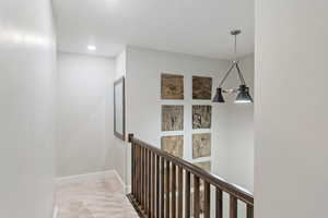 Corridor featuring light carpet and a textured ceiling