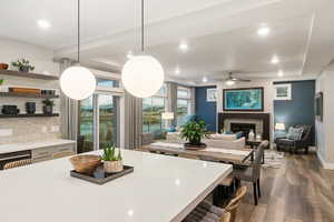 Kitchen with pendant lighting, backsplash, hardwood / wood-style flooring, ceiling fan, and a tray ceiling