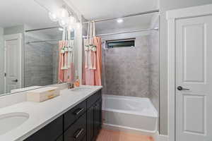 Bathroom with tile patterned flooring, vanity, and shower / bathtub combination with curtain