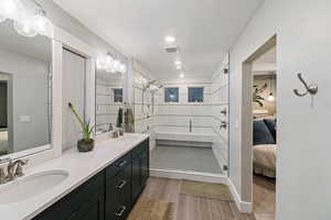 Bathroom with vanity, wood-type flooring, and tiled shower