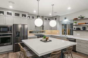 Kitchen with gray cabinetry, a breakfast bar, high quality appliances, sink, and hanging light fixtures