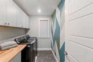 Laundry area featuring cabinets, washer and dryer, and dark wood-type flooring