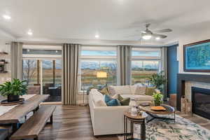 Living room with a tiled fireplace, ceiling fan, and wood-type flooring