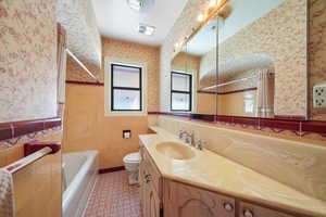 Bathroom with tile patterned flooring, vanity, toilet, and tile walls