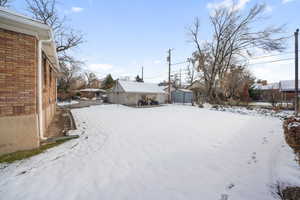 Yard covered in snow featuring a garage and an outdoor structure