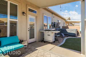 View of patio featuring area for grilling and a hot tub