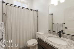 Bathroom with vanity, a shower with shower curtain, and toilet