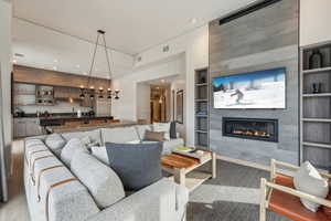 Living room with a tile fireplace, built in features, and wood-type flooring