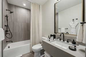 Full bathroom with toilet, shower / bath combo with shower curtain, and sink