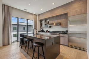 Kitchen with a wealth of natural light, light hardwood / wood-style floors, stainless steel appliances, and range hood