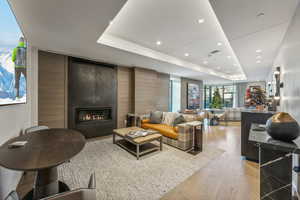 Living room with light hardwood / wood-style floors, a fireplace, and a tray ceiling