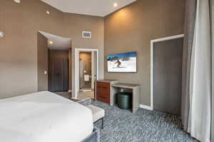 Bedroom featuring dark colored carpet and connected bathroom