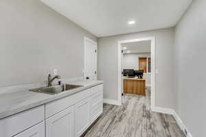 Kitchen featuring light hardwood / wood-style floors, white cabinetry, and sink