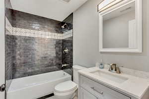 Full bathroom with toilet, vanity, and tiled shower / bath