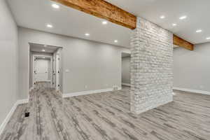 Unfurnished living room featuring beamed ceiling and light hardwood / wood-style floors