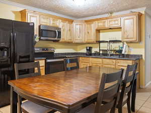 Kitchen featuring crown molding, sink, light tile patterned floors, a textured ceiling, and appliances with stainless steel finishes