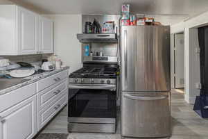 Kitchen featuring dark wood-type flooring, white cabinets, sink, appliances with stainless steel finishes, and extractor fan