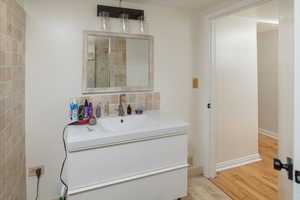 Bathroom featuring decorative backsplash, hardwood / wood-style floors, and vanity