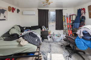 Bedroom featuring a wall mounted AC and a notable chandelier