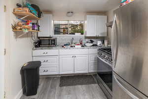 Kitchen featuring white cabinets, sink, decorative backsplash, dark hardwood / wood-style floors, and appliances with stainless steel finishes