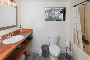 Full bathroom with vanity, wood-type flooring, shower / bath combo, and toilet