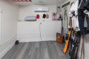 Laundry room with hardwood / wood-style flooring and a wall mounted AC