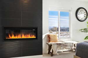 Living area featuring a large fireplace, carpet floors, and a healthy amount of sunlight