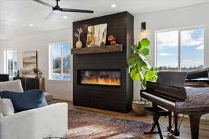 Living room featuring a large fireplace, a wealth of natural light, hardwood / wood-style floors, and ceiling fan