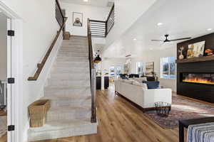 Staircase featuring hardwood / wood-style flooring, ceiling fan, and a large fireplace