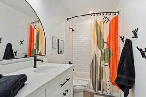 Full bathroom with toilet, vanity, and shower / tub combo with curtain