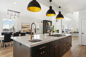 Kitchen with appliances with stainless steel finishes, decorative light fixtures, a kitchen island with sink, and sink