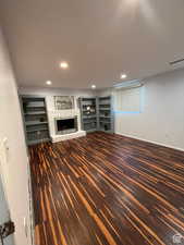 Unfurnished living room with dark hardwood / wood-style flooring and a brick fireplace