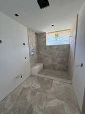 Bathroom featuring tiled shower and marble finish flooring