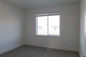 Spare room featuring plenty of natural light and dark colored carpet