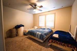 Carpeted bedroom featuring ceiling fan and a textured ceiling