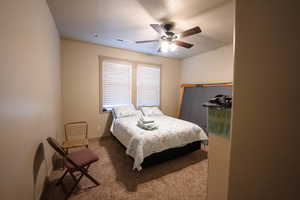 Bedroom with ceiling fan, carpet floors, and a textured ceiling