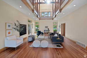 Living room with hardwood / wood-style floors, a towering ceiling, and a wealth of natural light