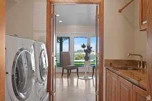 Clothes washing area featuring cabinets, french doors, and sink