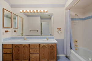 Bathroom with tile patterned floors, vanity, shower / tub combo, and ornamental molding