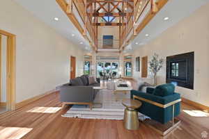 Living room with french doors, a towering ceiling, and light wood-type flooring