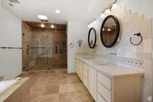 Bathroom featuring vanity, backsplash, and plus walk in shower