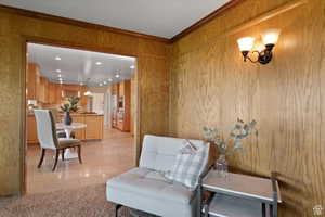 Living area featuring wooden walls, light tile patterned flooring, and ornamental molding