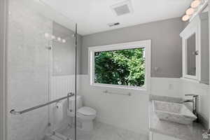 Bathroom featuring vanity, toilet, and a shower with shower door