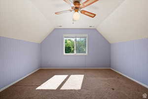 Additional living space featuring ceiling fan, light colored carpet, and vaulted ceiling