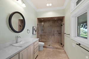 Bathroom with ornamental molding, vanity, a shower with door, tile patterned flooring, and toilet