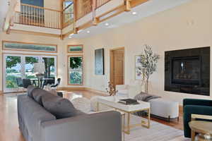 Living room featuring a fireplace, a high ceiling, and light hardwood / wood-style flooring