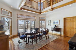 Dining room with a high ceiling, hardwood / wood-style flooring, and a healthy amount of sunlight