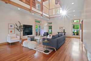 Living room with hardwood / wood-style floors, a towering ceiling, a tile fireplace, and french doors